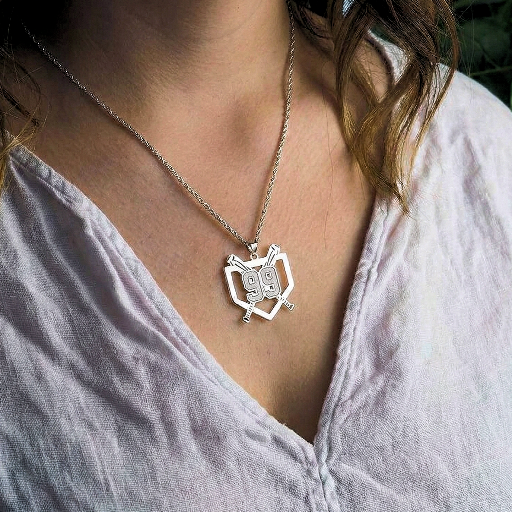 Woman wearing baseball-themed necklace with pendant over shirt