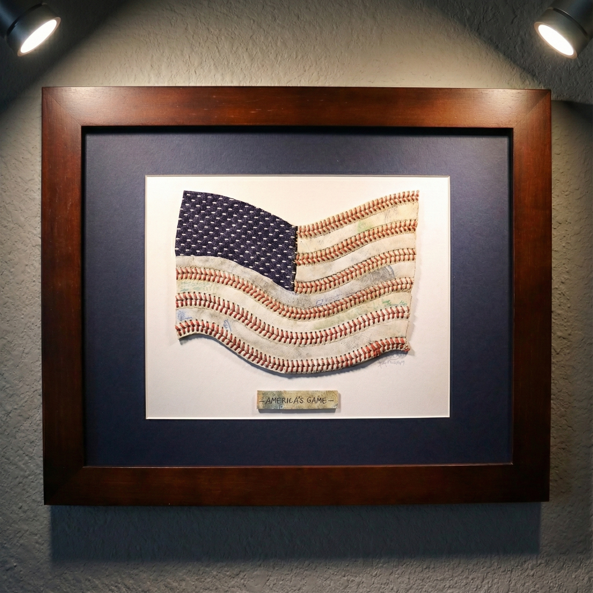 Framed baseball wall art featuring American flag made from baseball stitching hanging on wall