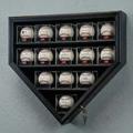 Black home plate-shaped baseball display case with signed baseballs on a gray wall