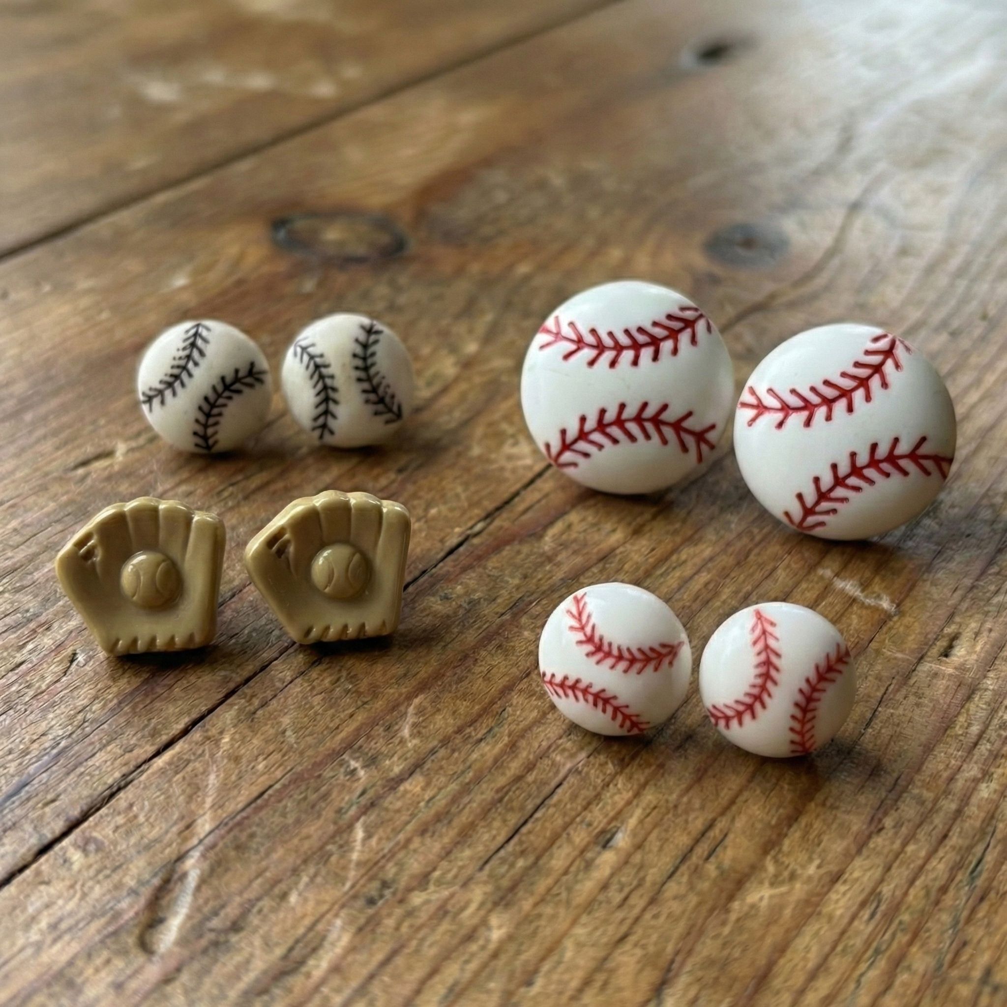 Baseball-themed button post earrings on a wooden surface