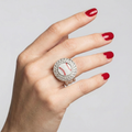 Hand wearing a ring with a baseball design on a plain background