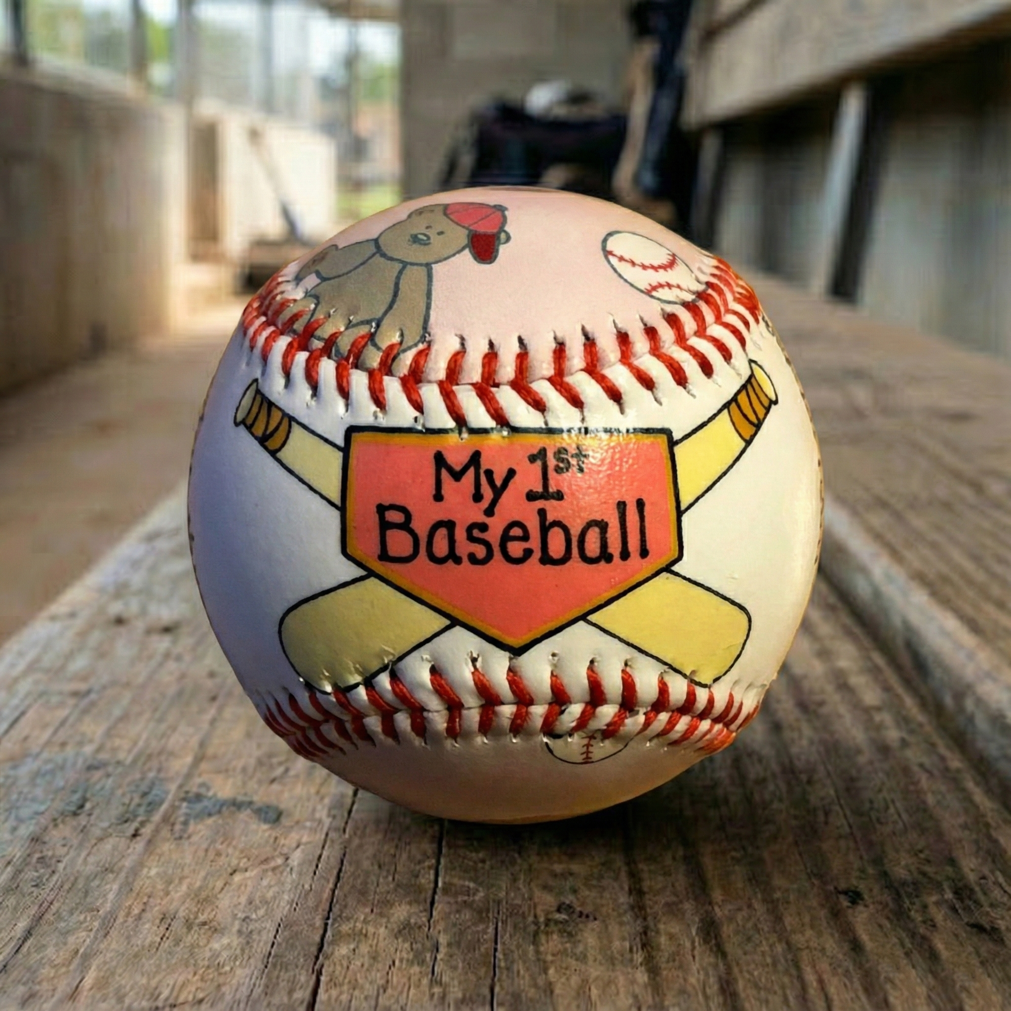 my first pink baby girl gift baseball on a dugout bench at the ball field.