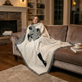 Woman sitting on a couch with a blanket featuring a baseball batter design in a cozy living room.
