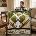 Man sitting on a couch with a baseball-themed blanket that says 'Thanks Coach!' in a living room.