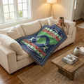Woman sitting on a couch with a baseball field blanket, in a cozy living room.