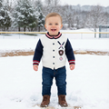 Child wearing a baseball patterned sweater and jeans standing in the snow.