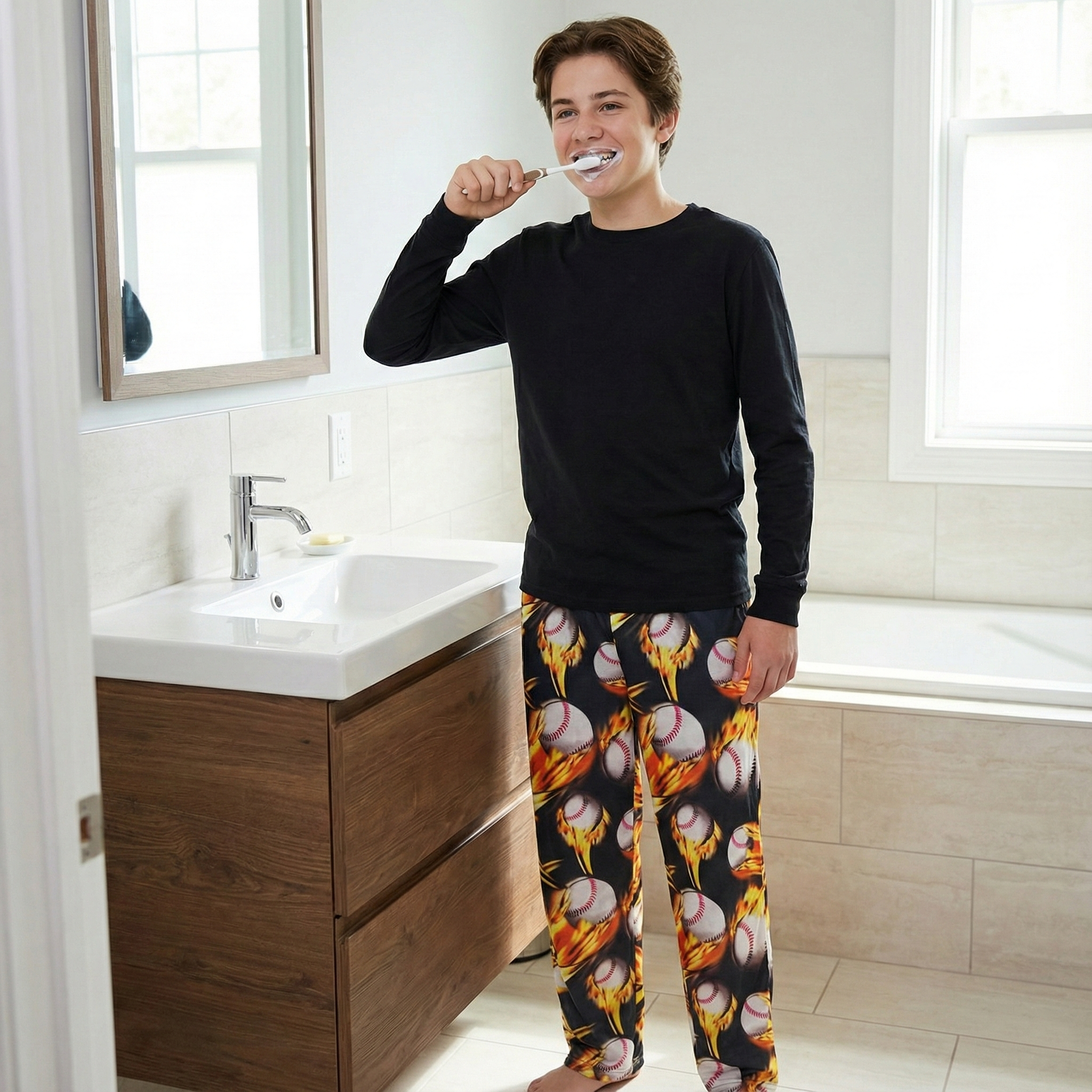 Person brushing teeth in a bathroom wearing black pajama top and colorful fire baseball pajama pants.