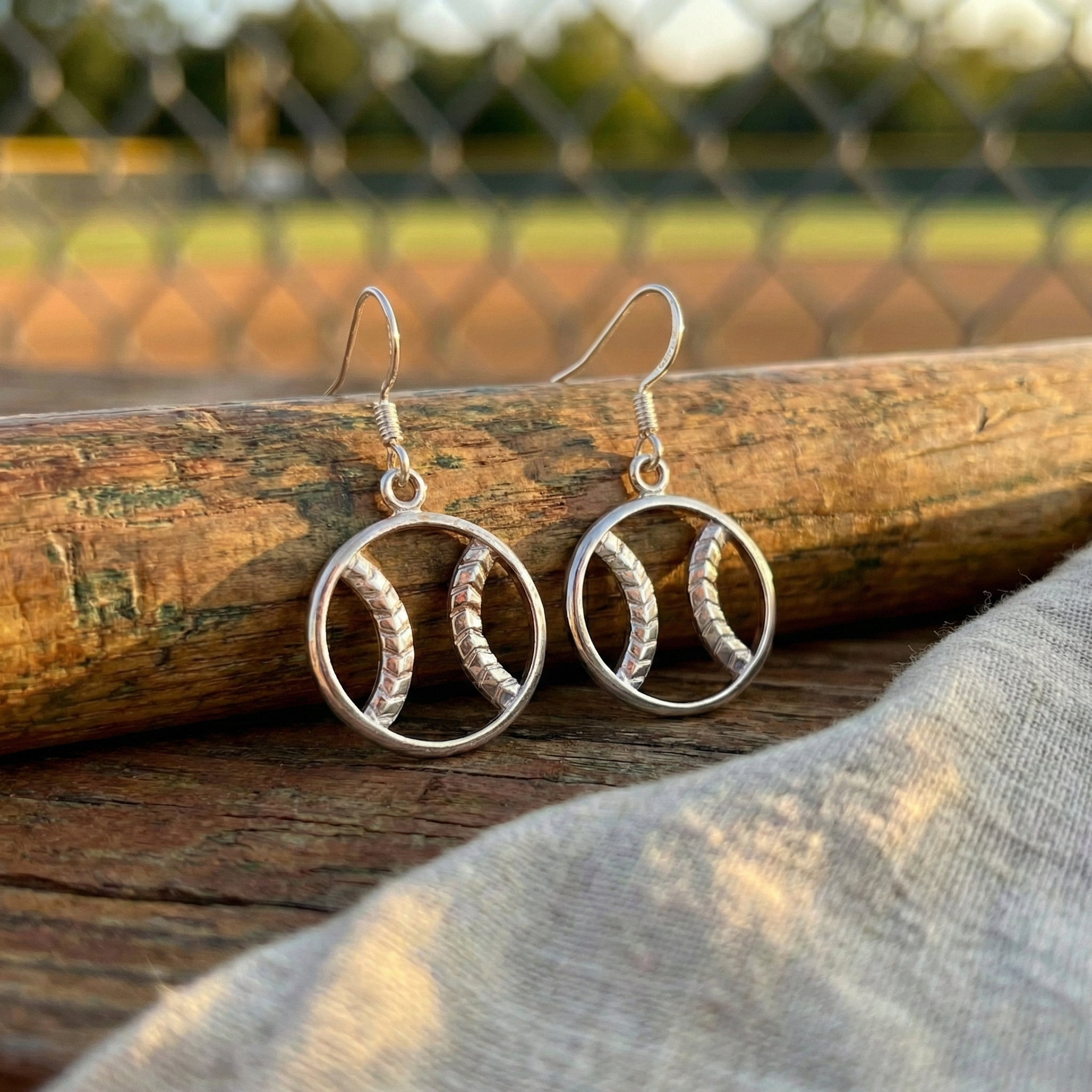 Sterling siver baseball zen earrings on a wooden surface with a blurred natural background