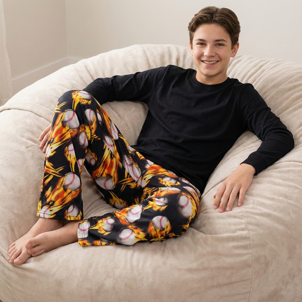 Person wearing a black long-sleeve shirt and colorful baseball-themed flaming fire pants sitting on a beige bean bag chair.