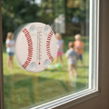Baseball-shaped thermometer on a window with children playing outside