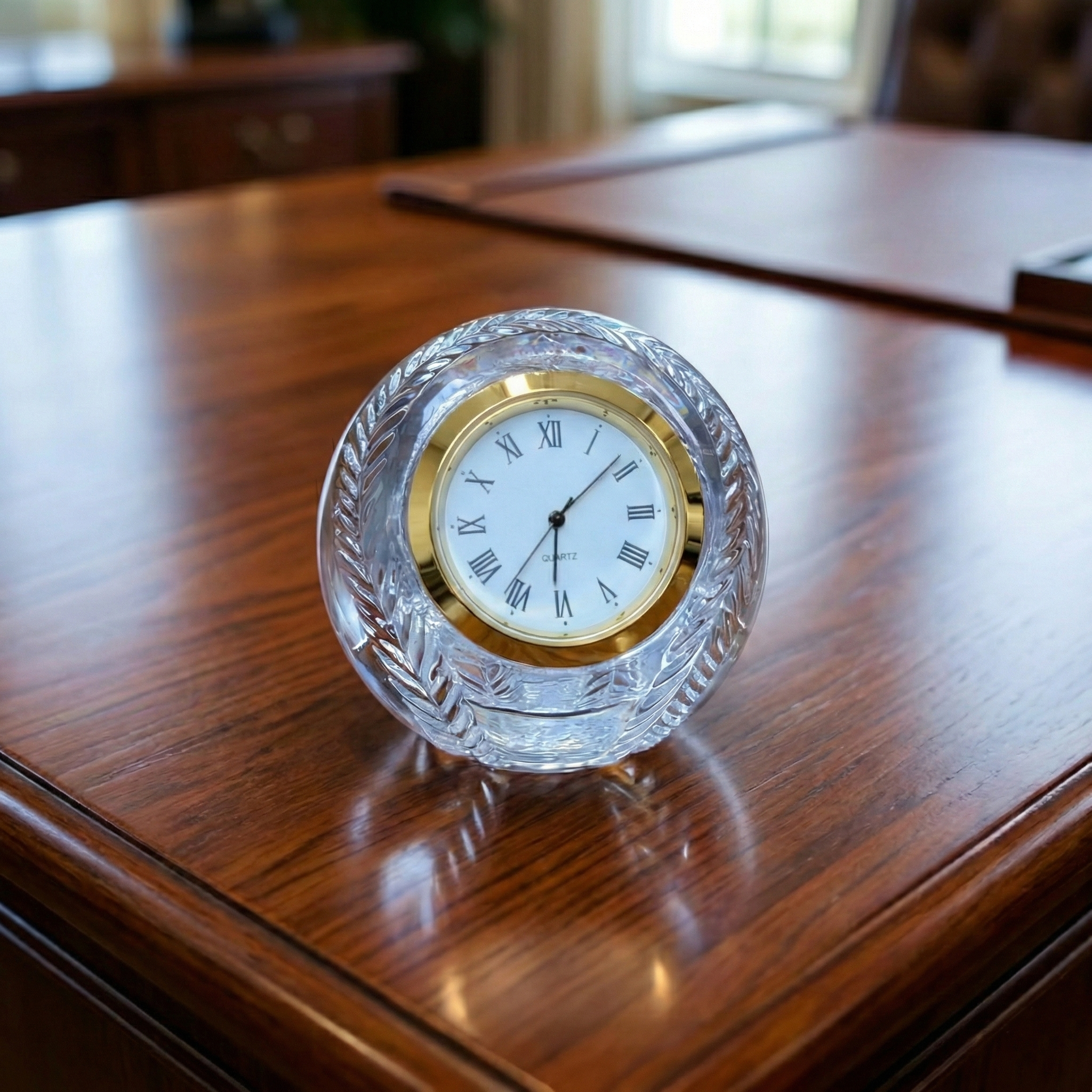 Crystal glass baseball clock with gold rim and crystal base on a wooden surface