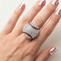 Hand wearing a baseball-shaped ring with diamond-like stones on a light background