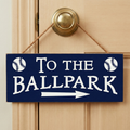 Decorative sign with 'To the Ballpark' text and baseball graphics on a wooden door.