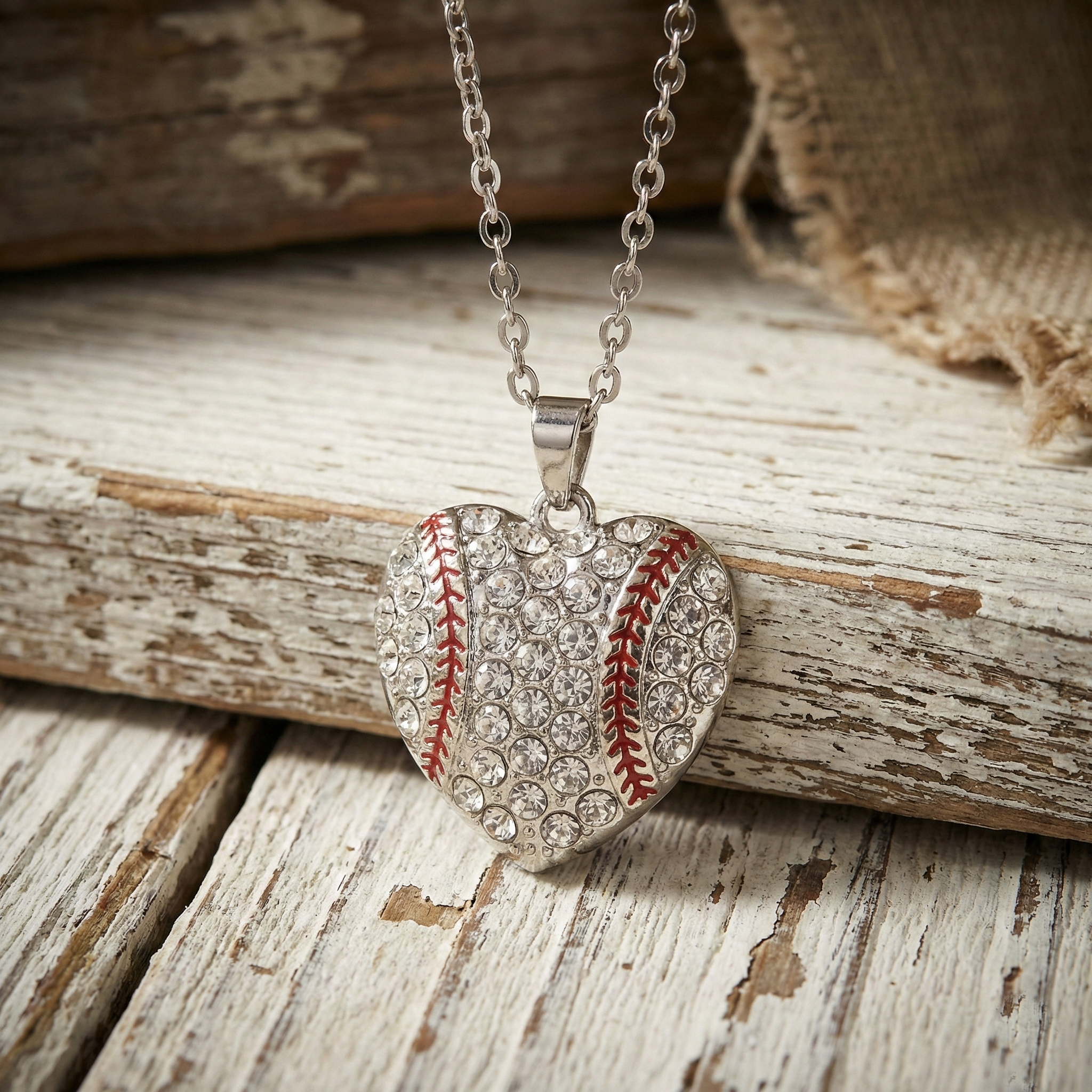 Heart-shaped baseball pendant silver necklace on a rustic wooden surface