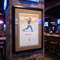 Framed Gold Ted Williams Signed Autographed Serigraph Print by Carlo Beninati on a brick wall in a bar setting