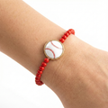 Red beaded bracelet with a baseball design on a wrist against a white background