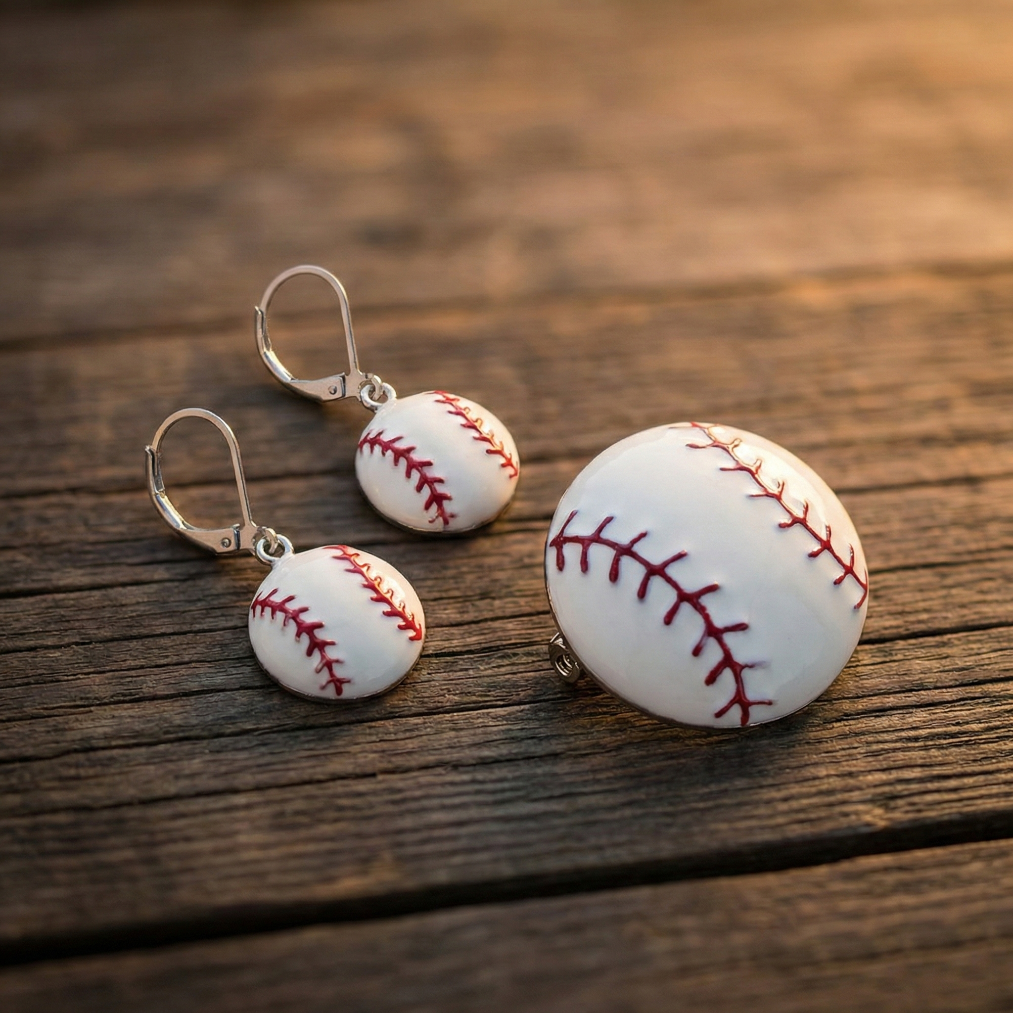 Baseball-shaped earrings and pin on a wooden surface