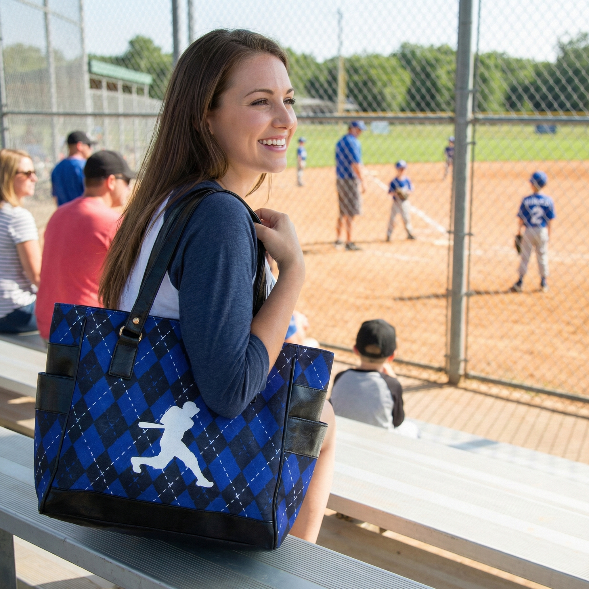 Woman holding a blue and black bag with a baseball player design at a baseball field.