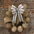 Decorative wreath made of used leather baseballs with a burlap bow on a wooden background