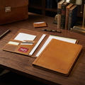 Rawlings Heart of the Hide Premium Tan Leather Portfolio with stationery on a wooden desk
