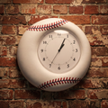 Wall clock designed like a baseball on a brick wall