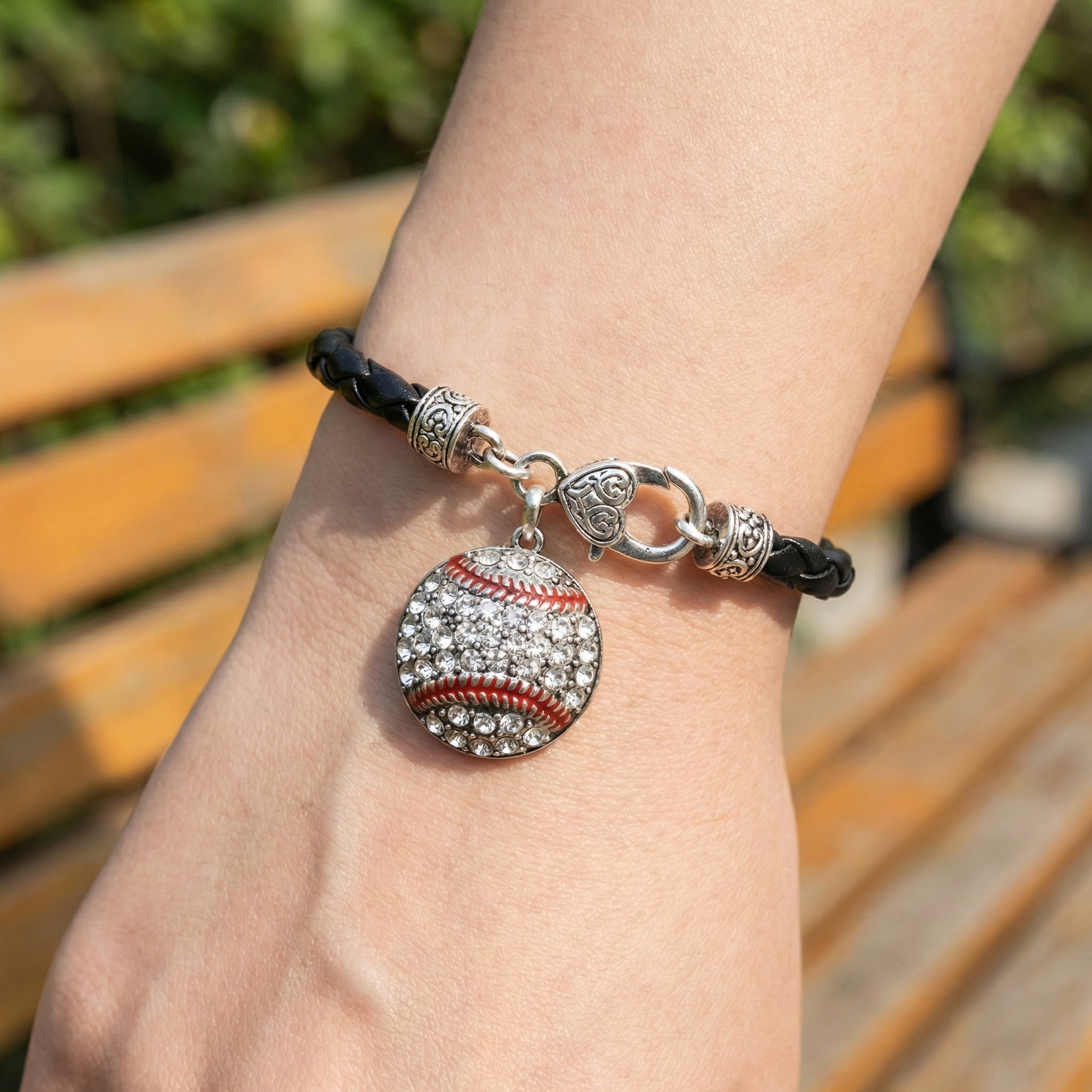 Bracelet with a baseball charm on a wrist, blurred outdoor background