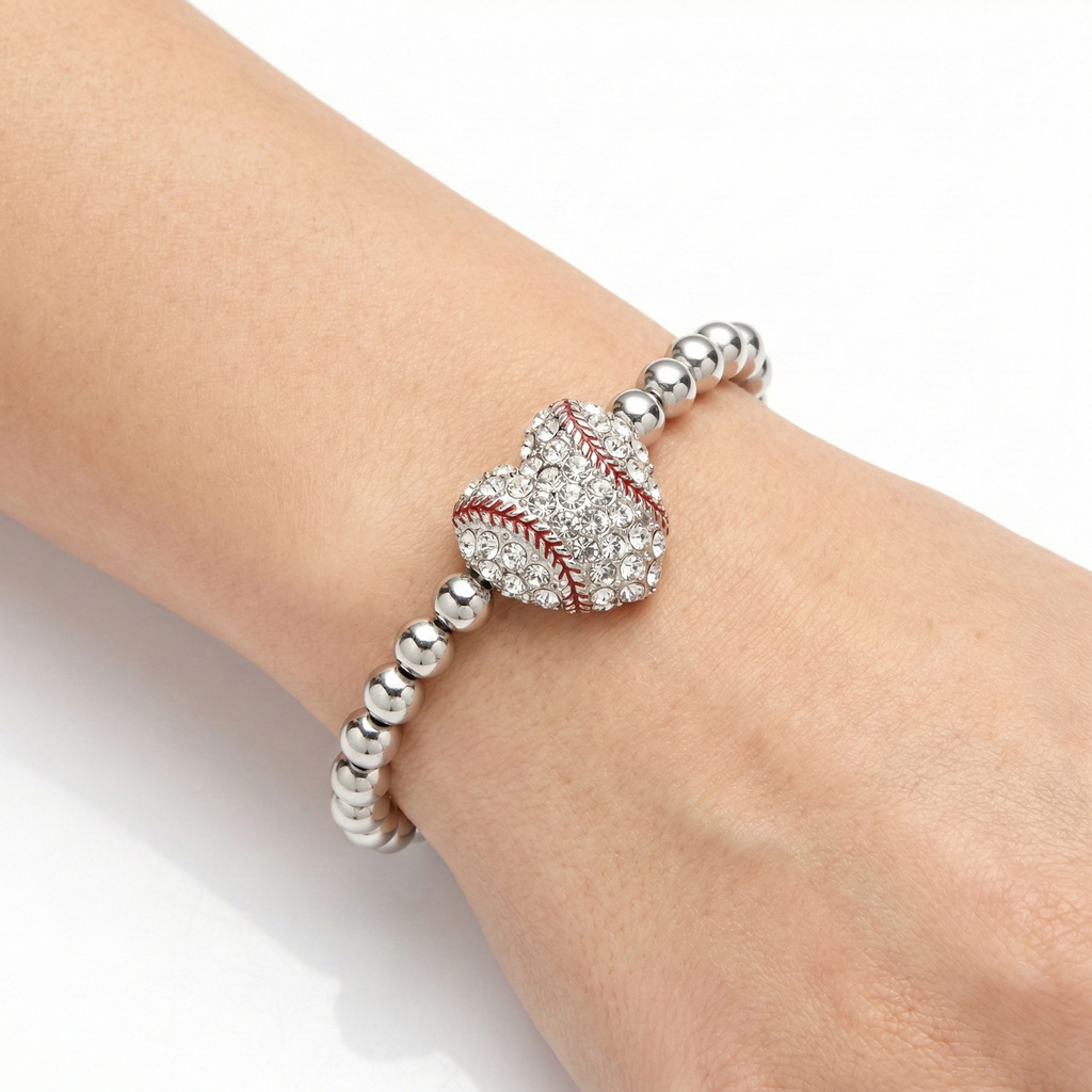 Silver bracelet with a baseball heart crystal charm on a wrist against a white background