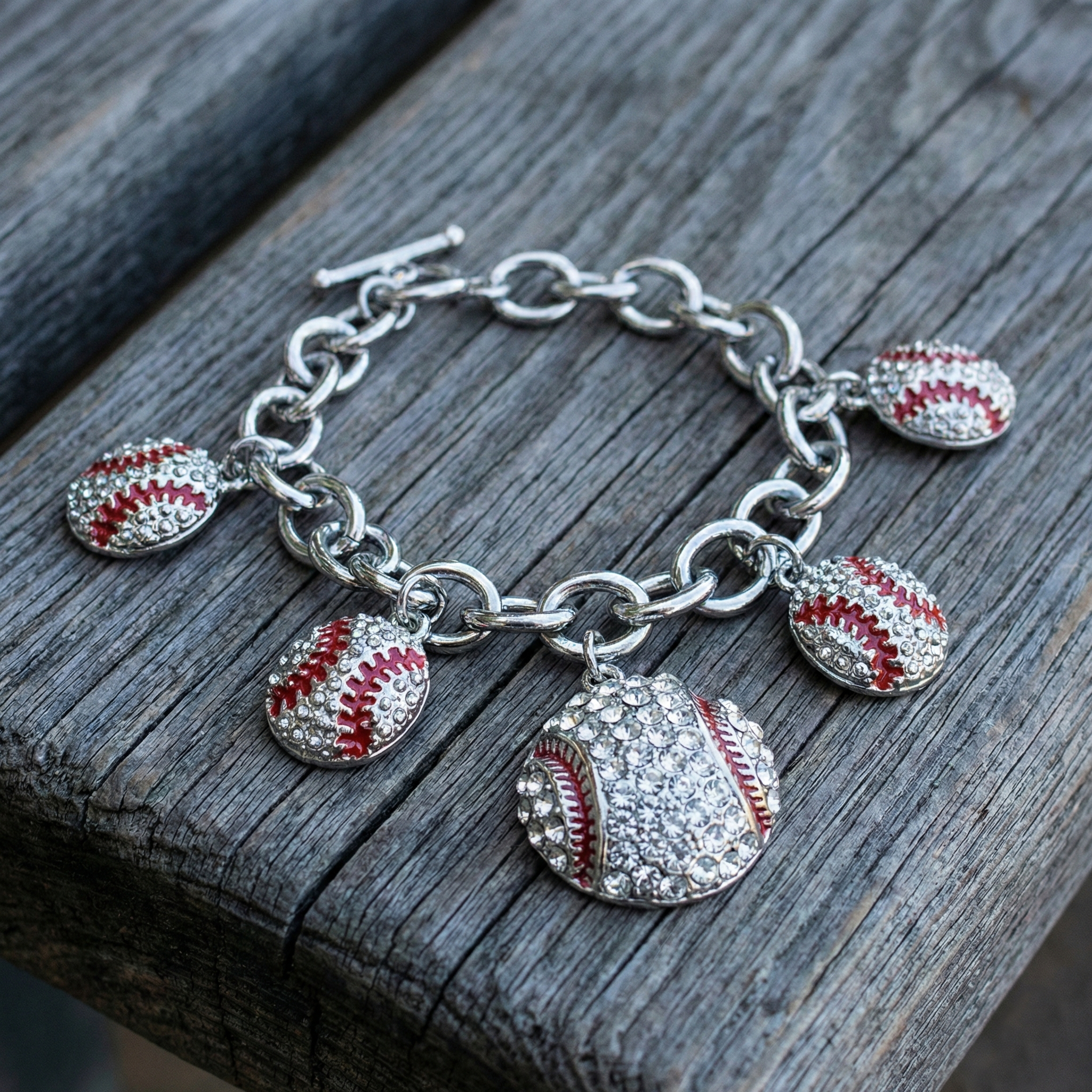 Silver bracelet with baseball charms on a wooden surface