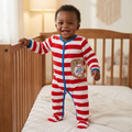 Baby in a red and white striped baseball velour onesie standing in a crib.