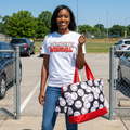 Woman holding a tote bag with baseball pattern in a parking lot