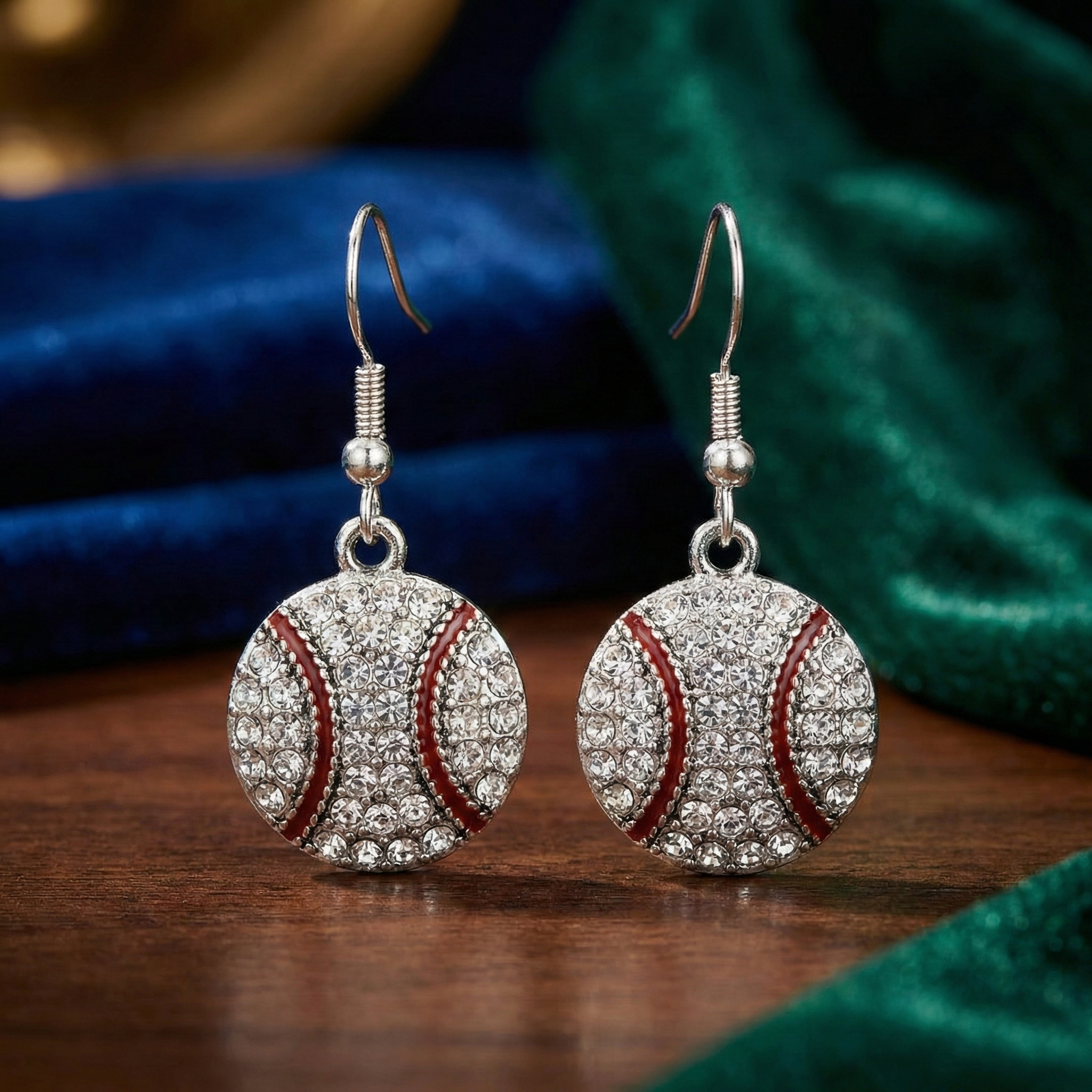 Silver baseball-shaped earrings with red accents on a wooden surface.