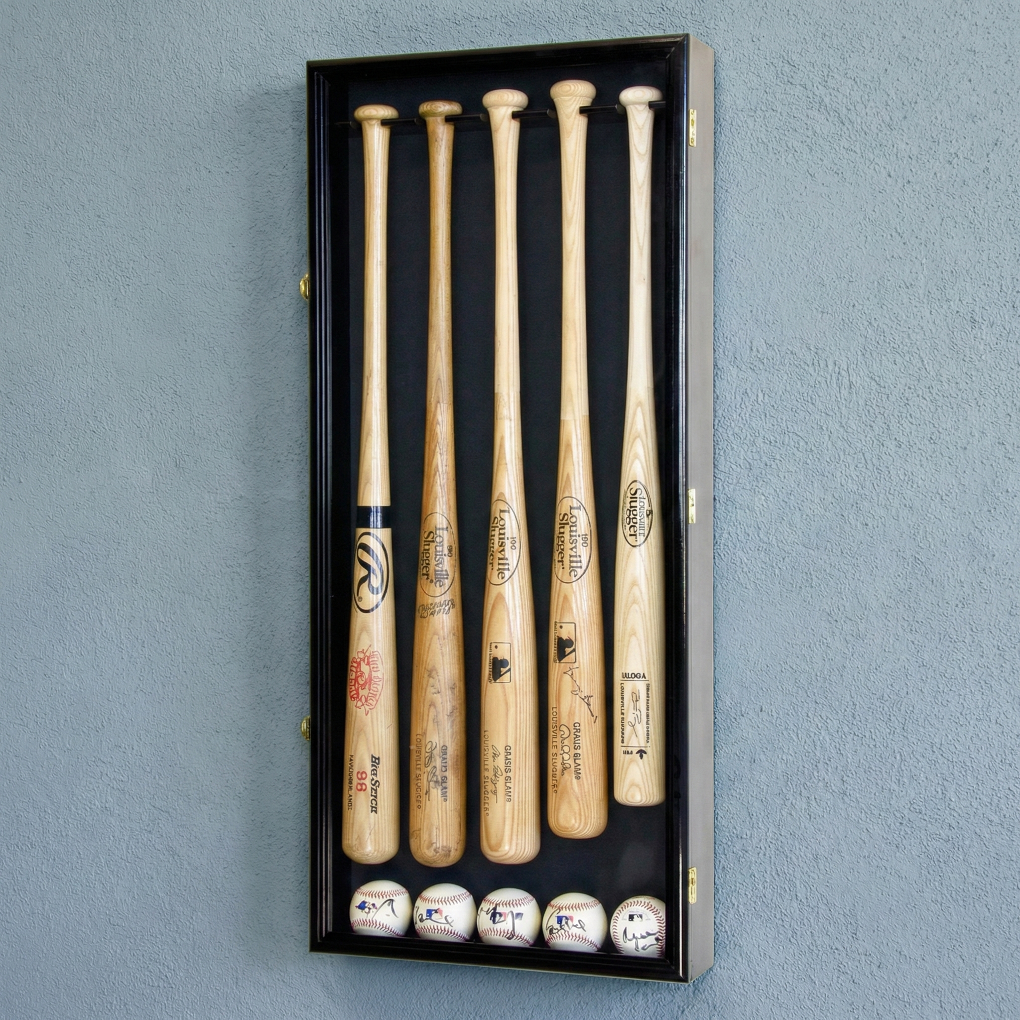 Set of five baseball bats in a black display case against a gray wall.