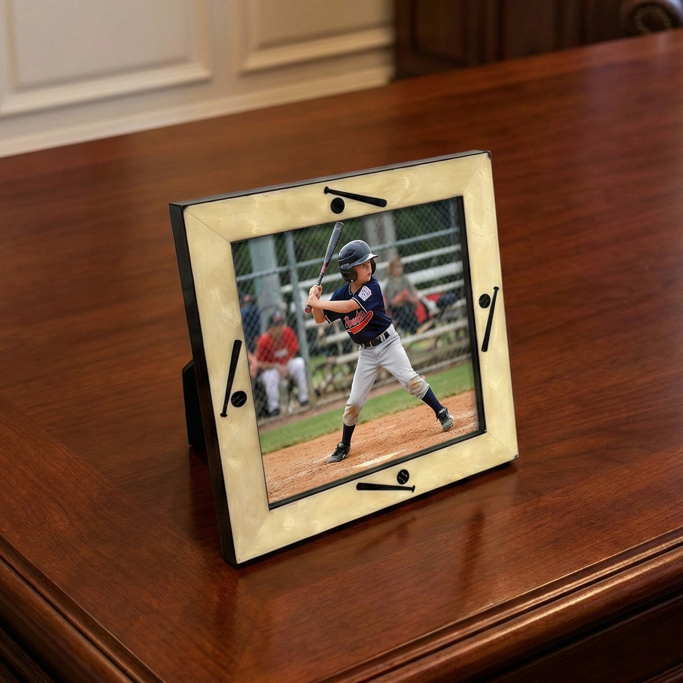 Decorative picture frame with a baseball player on a field, placed on a wooden surface.