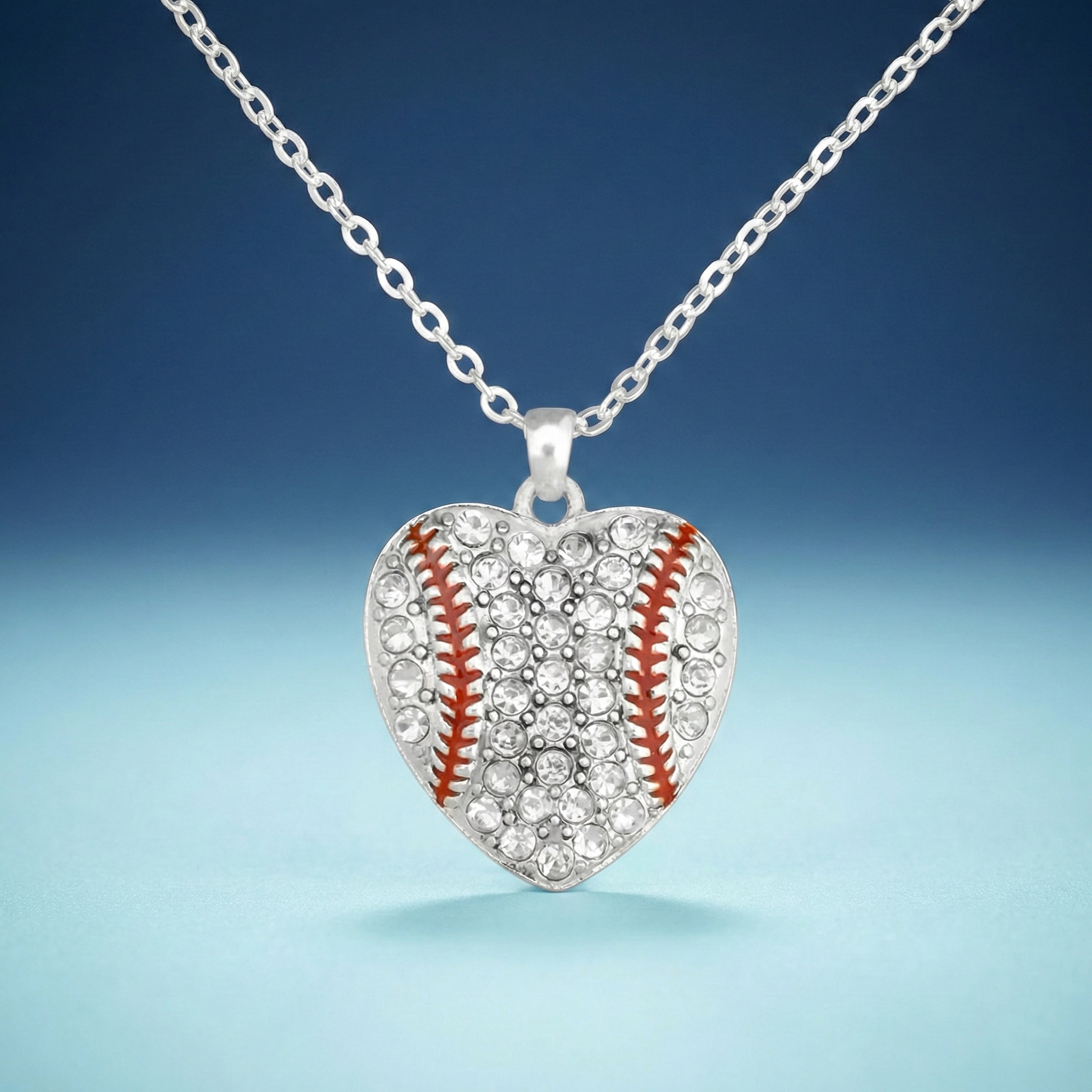 Heart-shaped necklace pendant with baseball design on a blue background