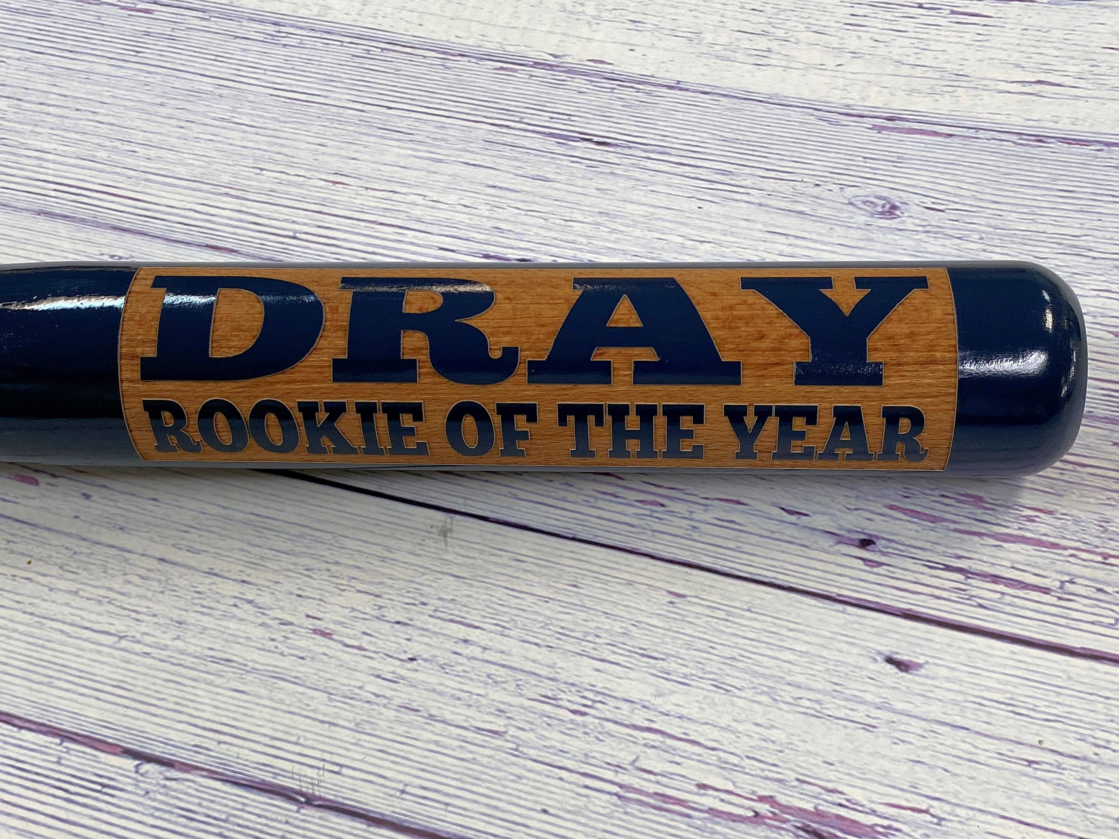 Engraved baseball bat with 'DRAY ROOKIE OF THE YEAR' engraving on a wooden surface