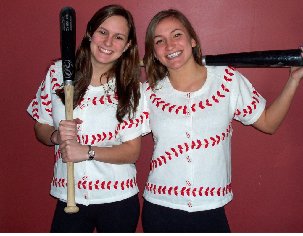 Two women wearing white baseball shirts with red stitching design, holding baseball bats against a red background.