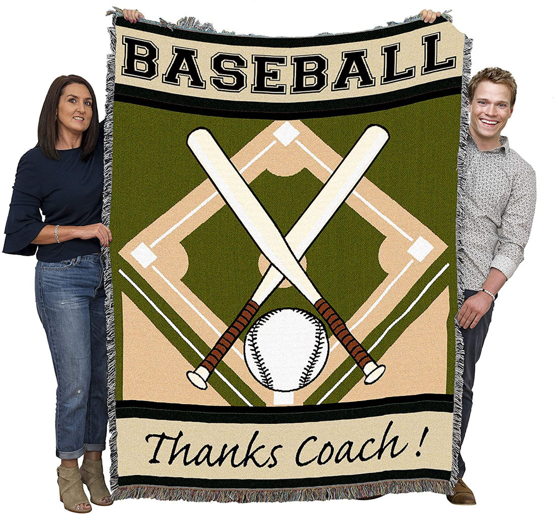 Two people holding a baseball-themed tapestry throw blanket with Thanks Coach crossed bats and a ball on a green field design.