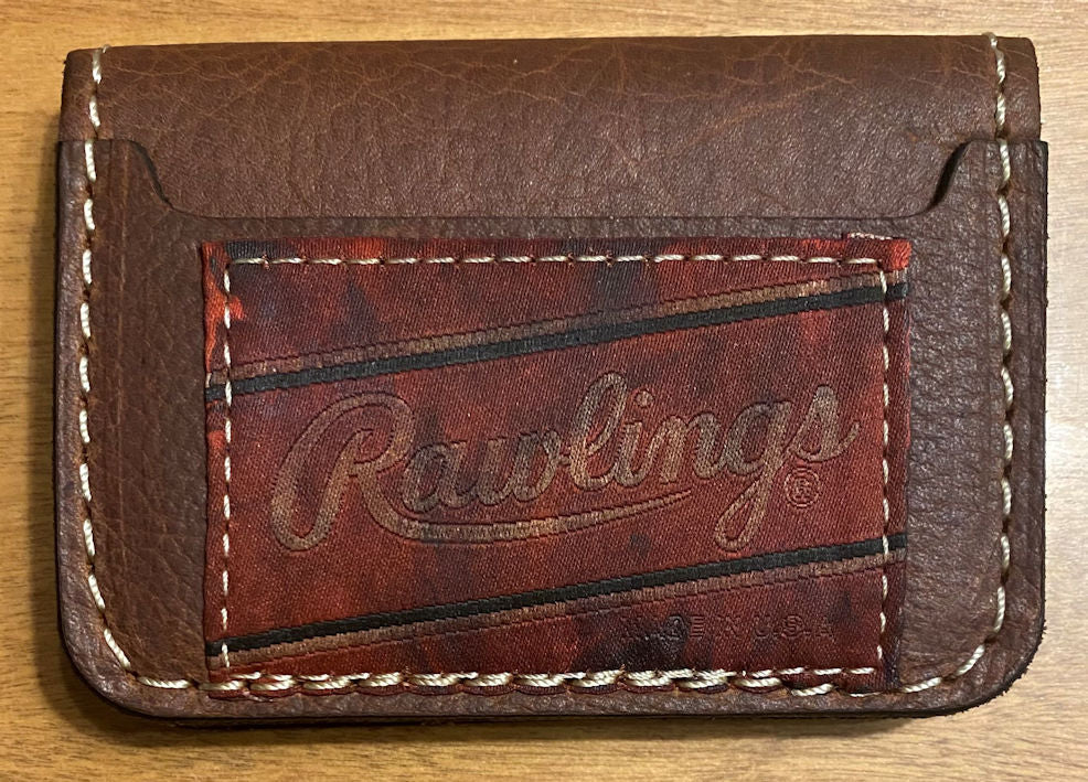 Brown leather wallet with 'Rawlings' branding on a wooden surface