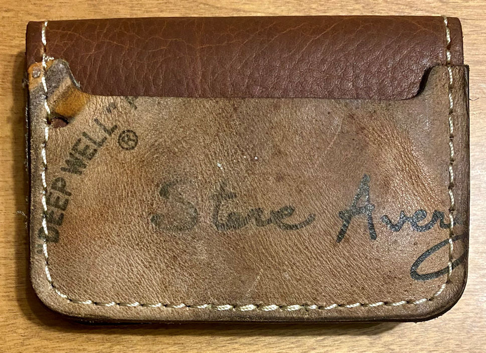 Brown leather baseball glove wallet with Steve Avery branding on a wooden surface