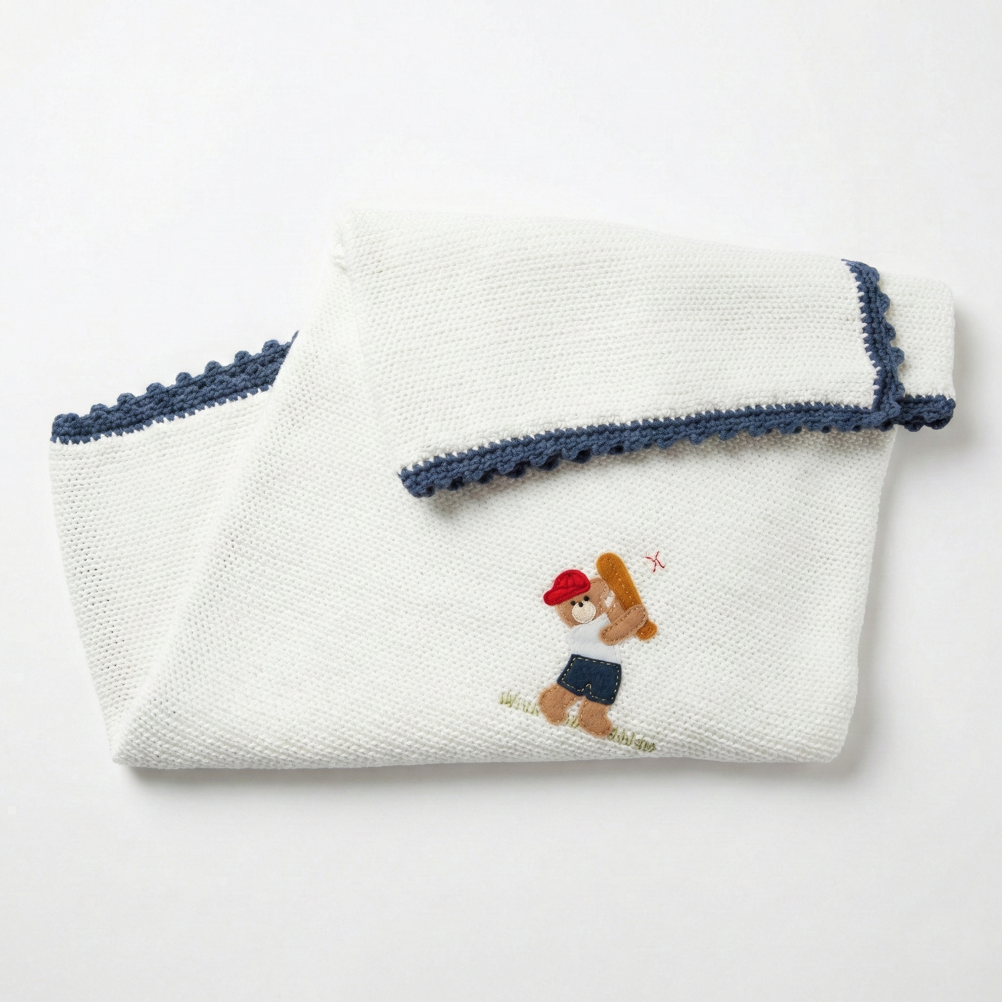 Folded white baseball bear baby blanket with embroidered design on a light gray background