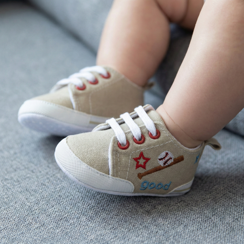 beige baseball baby sneakers with red accents and text on a gray surface