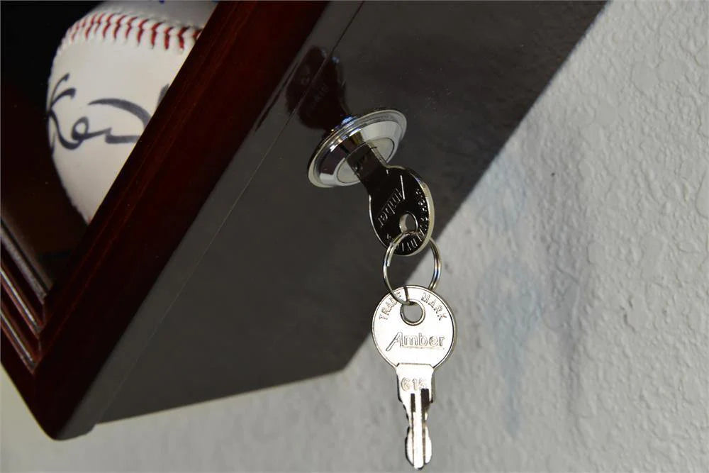 Close-up of a key attached to a keychain with a baseball in the background.