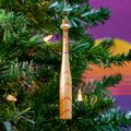 Decorative baseball bat shaped ornament on a Christmas tree with a colorful background