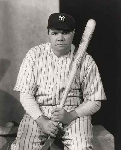 Vintage black and white photo of Babe Ruth the legendary baseball player in a Yankees pinstripe uniform holding a bat.
