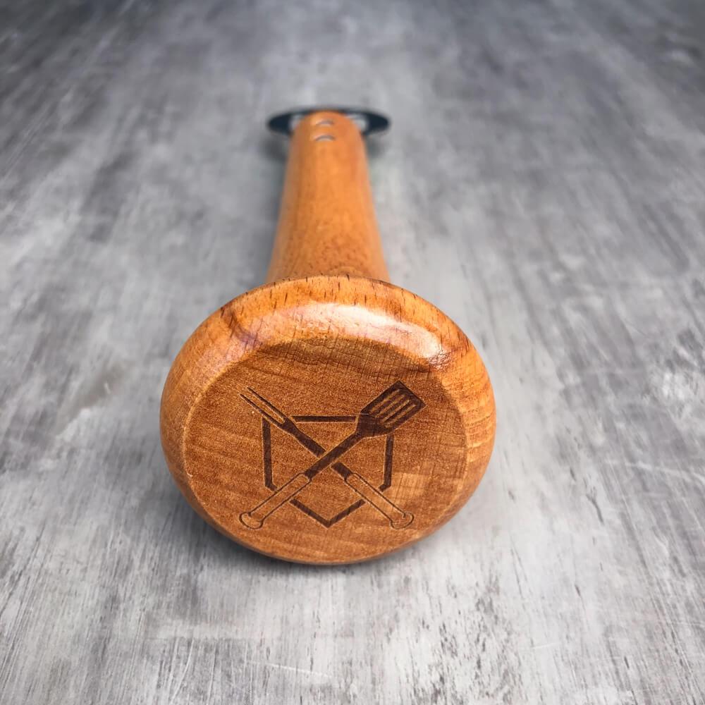 Wooden baseball bat bottle opener with engraved design on a gray surface
