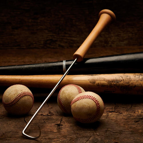 Baseball bat, baseballs, and a metal grill hook tool on a wooden surface with a dark background