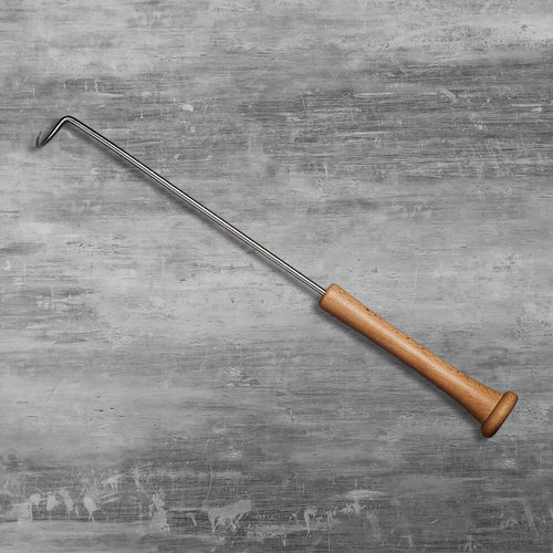Metal grill tool with wooden baseball bat handle on a gray textured surface
