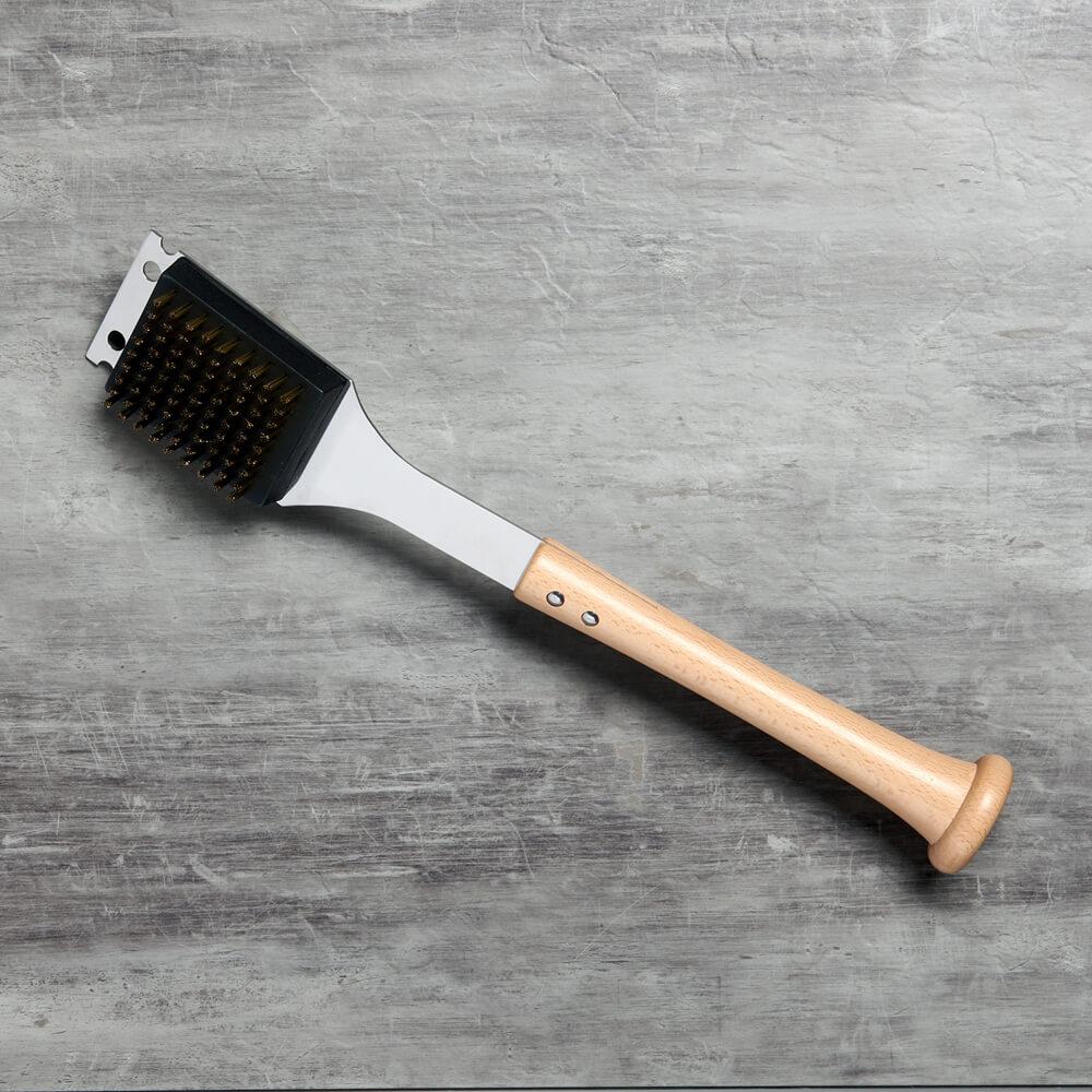 Barbecue brush and scraper with wooden baseball bat handle on a gray surface