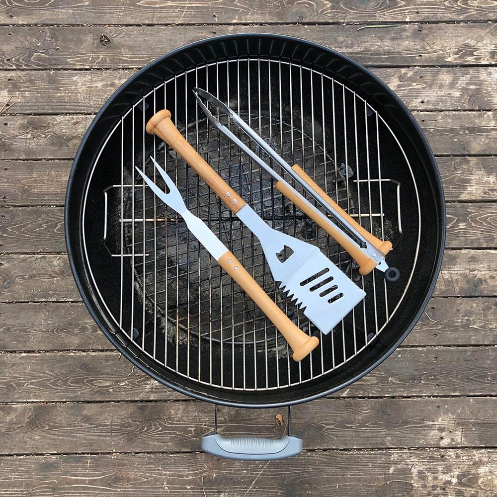 Barbecue grill with baseball bat utensils on a wooden surface