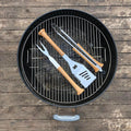 Barbecue grill with baseball bat utensils on a wooden surface